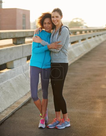 Foto de Incluso correr es mejor con una mejor amiga. Retrato de dos corredoras abrazándose y riéndose antes de correr por la ciudad - Imagen libre de derechos