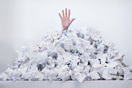 Photo for Help Im drowning in paperwork. A hand reaching up from beneath a pile of papers - Royalty Free Image