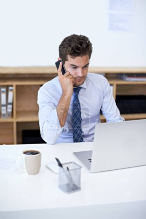 Foto de Ayudar a un cliente por teléfono. Un joven empresario atendiendo una llamada en su oficina - Imagen libre de derechos