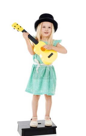 Foto de Lo hago por los fans. Estudio disparo de una linda niña jugando con su guitarra de juguete sobre un fondo blanco - Imagen libre de derechos