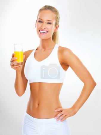 Foto de Lleno de vitaminas. Estudio de una joven en forma en ropa de gimnasio beber jugo - Imagen libre de derechos