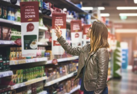 Photo for Shopping, woman at grocery store and in aisle searching and decision for product on a shelf. Customer or consumer, shopper for groceries and female person at supermarket or a shop looking for food. - Royalty Free Image