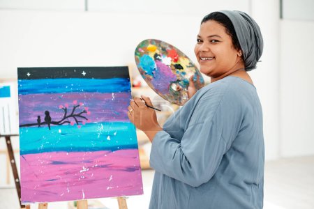 Photo for Enjoying every moment in this art class. Cropped portrait of an attractive young artist standing alone and painting during an art class in the studio - Royalty Free Image