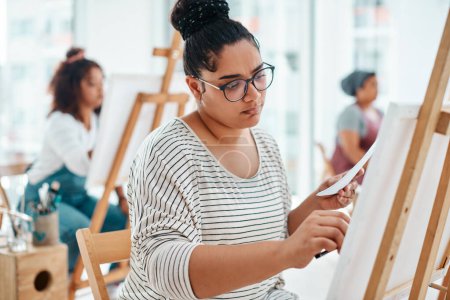 Foto de Pensamiento profundo. una atractiva joven sentada con sus amigos y pintando durante una clase de arte en el estudio - Imagen libre de derechos