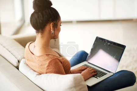 Photo for Woman on couch with laptop, typing for blog and freelance copywriter working from home. Female freelancer in living room, copywriting and writing on pc, technology and remote work with connectivity. - Royalty Free Image