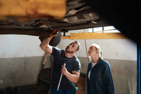 Foto de Aquí está el problema. dos mecánicos trabajando juntos bajo un coche levantado - Imagen libre de derechos