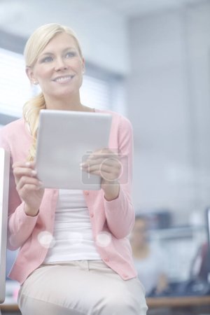 Photo for How did I ever cope without this thing. an attractive young businesswoman using a digital tablet - Royalty Free Image