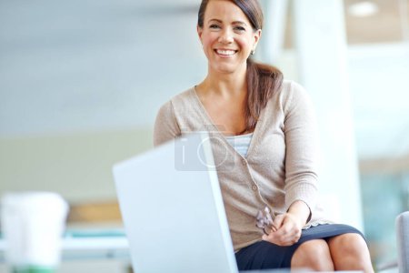 Foto de No podría pedirte un trabajo mejor. Retrato de una mujer de negocios sonriente sentada junto a un portátil en la oficina - Copyspace - Imagen libre de derechos
