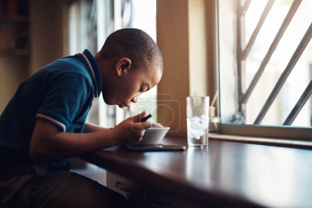 Foto de Creceré fuerte y saludable si termino toda mi comida. un niño comiendo un tazón de espagueti en casa - Imagen libre de derechos