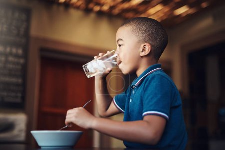 Foto de El agua ayuda a la digestión. un niño bebiendo agua con su comida en casa - Imagen libre de derechos