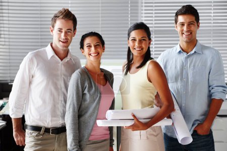Photo for Enthusiastic architects. A confident team of architects smiling at you while holding blueprints - Royalty Free Image