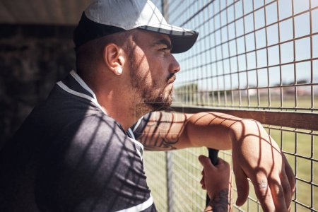 Foto de Cuando miramos, aprendemos. un joven mirando un partido de béisbol detrás de la valla - Imagen libre de derechos