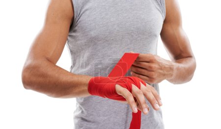 Photo for Strapping his hands for extra support. Cropped image of a kick-boxer strapping his hands with red .hand wraps against a white background - Royalty Free Image