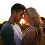 Sunset, love or couple in nature on romantic holiday vacation for bonding or relaxing on date together. Forehead, travel or people hug or embrace in summer with romance or peace in park in the dark.