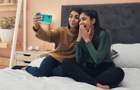 Foto de Jugando con filtros divertidos. dos mujeres jóvenes tomando una selfie juntas mientras están sentadas en casa - Imagen libre de derechos