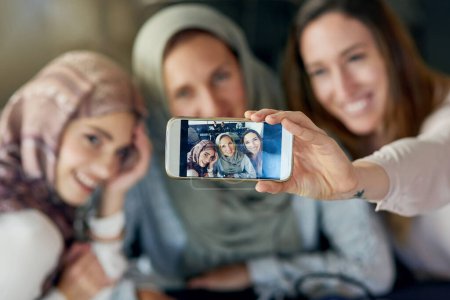 Photo for Muslim women, friends and selfie with phone, smile and happiness for post on blog, app or social network. Happy islamic woman, group and smartphone for photography, profile picture and memory on web. - Royalty Free Image