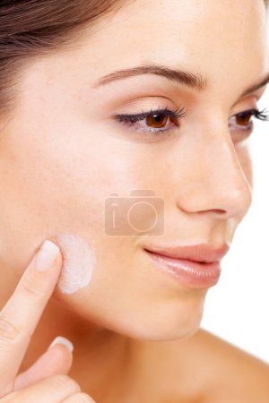 Foto de Manteniendo mi piel libre de arrugas. Imagen recortada de una mujer joven que se aplica loción en la cara - Imagen libre de derechos