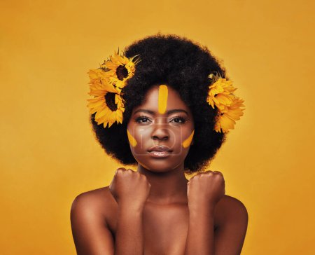 Photo for Beauty is power. Studio portrait of a beautiful young woman posing topless with sunflowers in her hair against a mustard background - Royalty Free Image