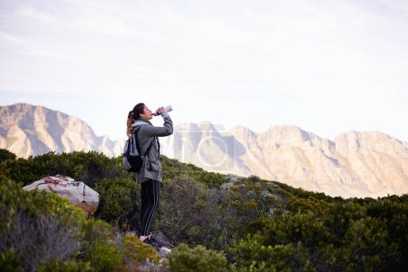 Photo for What a refreshing view. a young woman having a water break while out hiking - Royalty Free Image