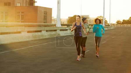Téléchargez les photos : Garde une longueur d'avance. trois amis jogging dans la ville tôt le matin - en image libre de droit