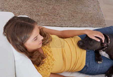 Téléchargez les photos : Il n'est jamais loin de mon côté. une jeune femme blonde allongée sur le canapé avec son chien à la maison - en image libre de droit