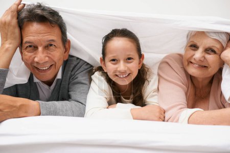 Foto de Retrato, abuelos o niños felices en el dormitorio para relajarse juntos para la unión en Australia con amor o cuidado. Mañana, rostros o abuela con chica divertida o anciano para disfrutar de tiempo de calidad en la cama. - Imagen libre de derechos