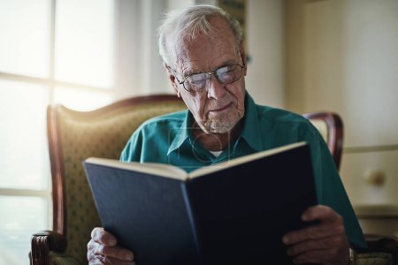 Foto de Nunca juzgues un libro por su portada. un hombre mayor leyendo un libro mientras se relaja en casa - Imagen libre de derechos