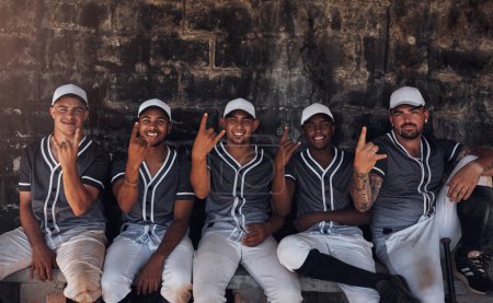 Foto de Fuera del campo es igual de divertido. un grupo de jóvenes jugadores de béisbol sentados en el dugout y mostrando signos de cuerno - Imagen libre de derechos