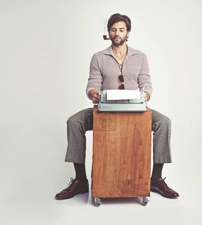 Foto de Volviendo a lo básico de la escritura. Un joven en ropa de estilo 70 usando una máquina de escribir - Imagen libre de derechos
