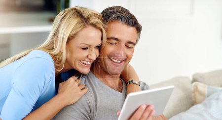 Téléchargez les photos : Faire des plans en ligne. un couple d'âge mûr utilisant une tablette numérique tout en se relaxant sur le canapé à la maison - en image libre de droit