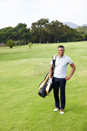 Téléchargez les photos : Viens faire un tour avec moi. Portrait d'un beau jeune homme debout sur un terrain de golf avec son sac de clubs - en image libre de droit