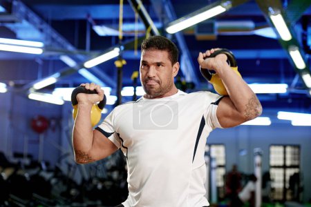 Foto de Bestia en las campanas. un hombre haciendo ejercicio con campanas de caldera en el gimnasio - Imagen libre de derechos