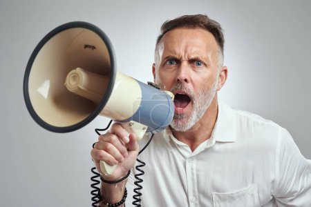 Photo for Open your ears and listen to me. Studio portrait of a mature man using a megaphone against a grey background - Royalty Free Image
