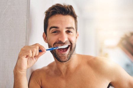 Portrait, toothbrush and happy man brushing teeth in morning for dental wellness, healthy habit and gums. Face of guy cleaning mouth for fresh breath, oral hygiene and routine in bathroom at home.