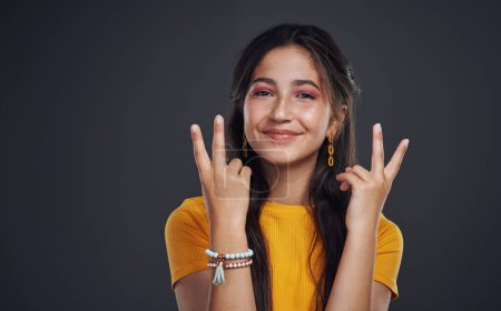 Photo for Spreading the peace. Cropped portrait of an attractive teenage girl standing alone and feeling playful against a dark background in the studio - Royalty Free Image