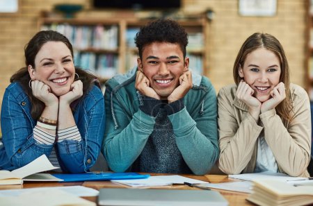 Foto de Compañeros de estudio alegres. Retrato de un grupo de estudiantes universitarios sentados en la biblioteca del campus - Imagen libre de derechos