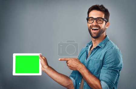 Photo for Happy man, tablet and pointing on mockup green screen for advertising against a grey studio background. Portrait of male person with smile showing technology display, chromakey or copy space branding. - Royalty Free Image