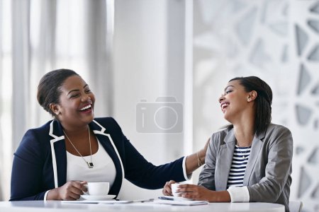 Téléchargez les photos : Rire sur le lieu de travail. deux collègues riant ensemble assis à un bureau dans un bureau - en image libre de droit