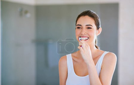 Foto de Cepillo de dientes, pasta de dientes y mujer cepillarse los dientes en el baño para la salud, la felicidad y el bienestar por la mañana. Chica, limpiando la boca para el cuidado dental y la higiene bucal o sonreír en casa con espacio de maqueta. - Imagen libre de derechos
