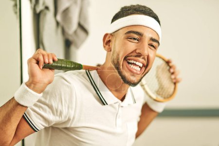 Téléchargez les photos : C'est un rire une minute dans ce club de squash. Portrait d'un jeune homme heureux tenant sa raquette de squash dans les vestiaires - en image libre de droit