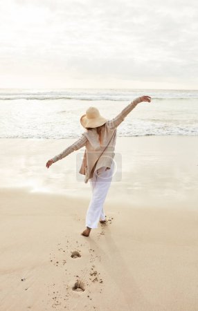 Photo for The sea has its own rejuvenating powers. Rearview shot of a young woman standing with her arms outstretched at the beach - Royalty Free Image