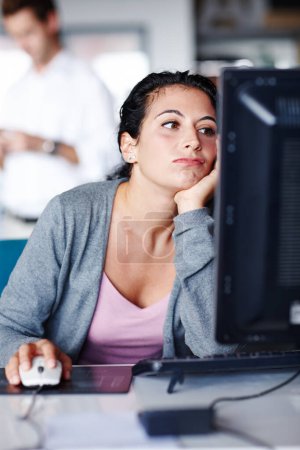 Foto de Necesito un nuevo trabajo... una joven empresaria aburrida mirando la pantalla de su computadora - Imagen libre de derechos