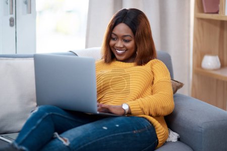 Foto de Mujer negra con portátil, sonrisa y relajarse en el sofá, buscar en línea para la película y la suscripción de streaming en casa. Mujer africana feliz en apartamento, conectividad y viendo en PC con internet. - Imagen libre de derechos