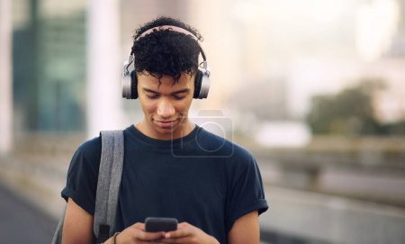 Photo for Phone, music and headphones with a man in the city, streaming an audio subscription service outdoor. Mobile, social media and backpack with a young male tourist outside in an urban town for travel. - Royalty Free Image