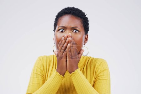 Shock, fear and scared woman in a studio with a omg, wow or wtf facial expression for emoji. Emotion, afraid and African female model with a surprise face with hands on her mouth by white background