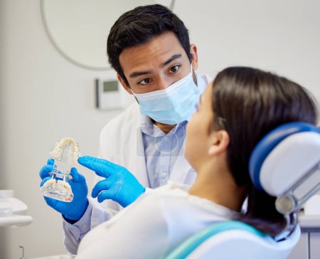 Téléchargez les photos : Il faudra peut-être extraire une dent. un dentiste montrant à sa patiente un modèle de dents avant son intervention - en image libre de droit