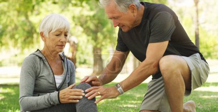 Photo for Old couple, woman with knee pain and injury in park, fibromyalgia health problem and joint ache from exercise. Man helping, arthritis and people in retirement with fitness outdoor and muscle tension. - Royalty Free Image