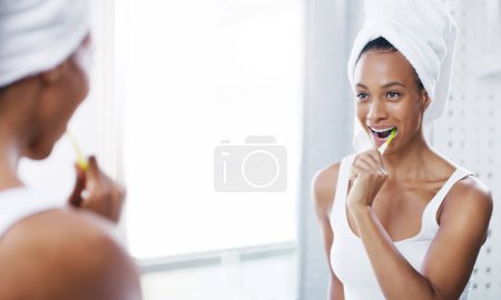 Foto de Mujer feliz cepillándose los dientes en el baño, espejo e higiene bucal, rutina matutina con cepillo de dientes y dental. Persona femenina en casa, aseo y cuidado personal, boca limpia con pasta de dientes y salud. - Imagen libre de derechos