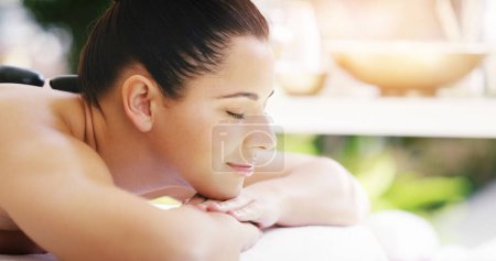 Photo for Woman, relax and sleeping in rock massage at spa for zen, physical therapy or treatment at resort. Happy and calm female person relaxing with hot stone for stress relief, peace or wellness at a salon. - Royalty Free Image