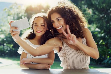 Photo for Mother, girl kid and selfie in garden with peace sign, happiness or smile in summer sunshine. Young mom, daughter and profile picture for social media, app or blog in backyard with bond, love or care. - Royalty Free Image